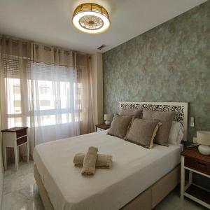 Un dormitorio con una gran cama blanca y una ventana en Apartamento reformado con vistas al mar, en Cádiz