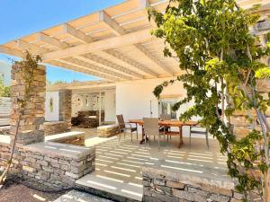 un patio con una mesa y una pared de piedra en Villa Santa Maria-Sophia en Kampos Paros