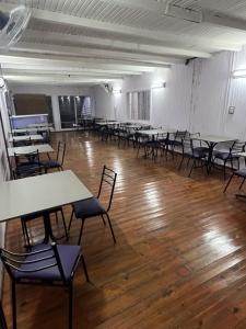 an empty room with tables and chairs and wooden floors at Wynwood Extreme Hostel in Villa Carlos Paz