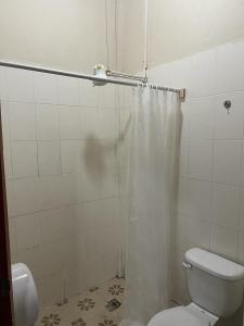 y baño con aseo y cortina de ducha. en Hotel Villa Margarita, en Flores