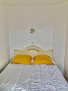 een wit bed met 2 gele kussens erop bij Les Restanques glycines 2066 in Grimaud
