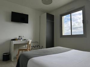 um quarto com uma cama, uma secretária e uma janela em Hôtel Restaurant Le Mur du Roy em Sarzeau