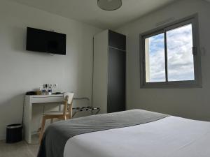 a bedroom with a bed and a desk and a window at Hôtel Restaurant Le Mur du Roy in Sarzeau +33 photos