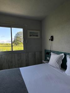 - une chambre avec un grand lit blanc et une fenêtre dans l'établissement Hôtel Restaurant Le Mur du Roy, à Sarzeau