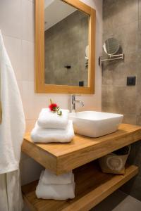 a bathroom with a sink and a mirror and towels at Nissos Apartments in Myrina