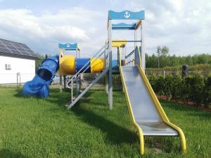a playground with a slide in the grass at OKej domki Łeba - Nowęcin in Nowecin