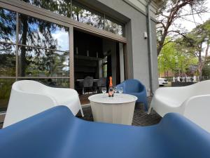 een patio met witte stoelen en een tafel met een fles wijn bij Villa Comfort in Palanga