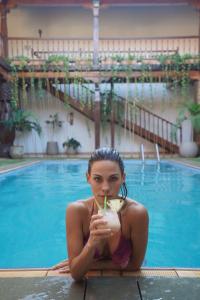 una mujer en bikini sosteniendo una bebida frente a una piscina en Hotel La Mision, en San Ignacio de Velasco