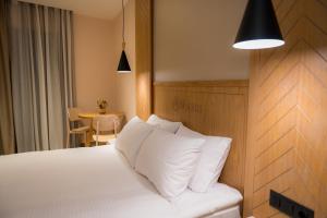 a bedroom with a bed with white pillows and a table at Nissos Apartments in Myrina