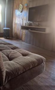 ein Sofa im Wohnzimmer mit einem TV an der Wand in der Unterkunft foresti macedo casa in Gramado