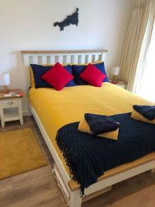 een slaapkamer met een groot bed met rode en blauwe kussens bij Bosun's Bude in Bude
