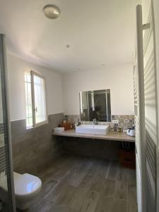 ein Badezimmer mit einem Waschbecken, einem WC und einem Spiegel in der Unterkunft Villa Comorebi Provence in Entrecasteaux