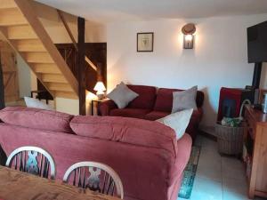 a living room with a red couch and a staircase at Badger Cottage in Salagnac