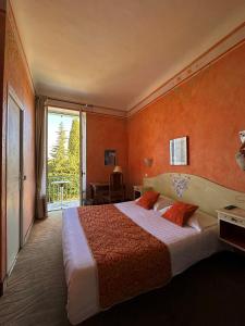 een slaapkamer met een groot bed met een oranje muur bij Hôtel Miramar in Vence