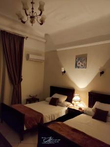 una camera d'albergo con due letti e un lampadario a braccio di Triomphe Hostel ad Alessandria d'Egitto
