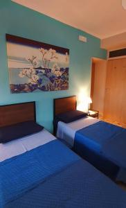 una camera d'albergo con due letti e un dipinto sul muro di Pacifico Rooms a San Bartolomeo in Galdo