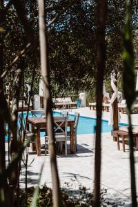 Una mujer parada junto a una mesa y sillas junto a una piscina. en Can Vistabella Boutique Resort, en San Antonio