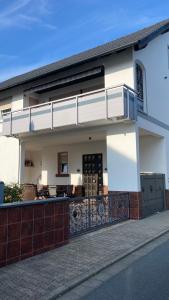 a white house with a balcony on a street at Ferienwohnung -Isola Madre in Biebesheim