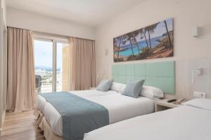 um quarto de hotel com duas camas e uma janela em Nordeste Playa em Can Picafort