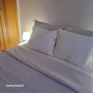 uma cama com almofadas brancas num quarto em Chez Najib et Ziad em Temara