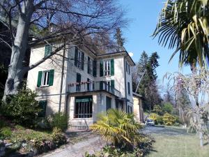 una casa blanca con persianas verdes y un árbol en Villa Virginia, en Varese