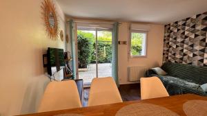 een woonkamer met een tafel en stoelen en een bank bij Appartement T2 Rez de jardin - Disneyland Paris 6 min in Bussy-Saint-Georges