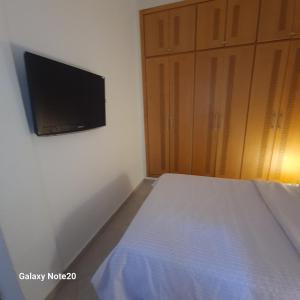 Schlafzimmer mit einem Bett und einem Flachbild-TV in der Unterkunft Chez Najib et Ziad in Temara