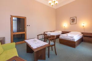 a room with two beds and a table and chairs at Hotel Slovan Plzeň in Pilsen
