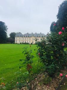 ein großes Gebäude auf einem grünen Feld mit rosa Rosen in der Unterkunft MAISON entre TERRE & MER - 132 M² - 2 Km de la MER in Saint-Léonard
