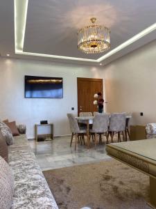ein Wohnzimmer mit einem Tisch, Stühlen und einem Kronleuchter in der Unterkunft cozy appartement with swimming pool in Agadir