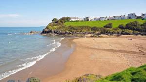 une plage de sable avec des maisons sur une colline à côté de l'océan dans l'établissement Katy’s Cwtch, à Cardigan
