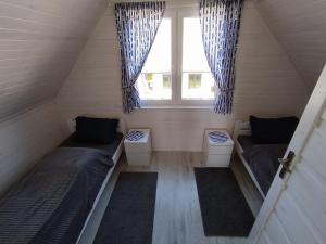 フウォピにあるDomki Letniskowe Neptun IIのベッド2台と窓が備わる小さな客室です。