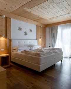 ein Schlafzimmer mit einem großen weißen Bett in einem Zimmer in der Unterkunft Chalet Le Coccole in Sappada