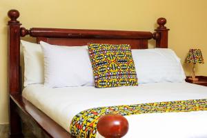 a bed with a wooden headboard and two pillows at Palm Star Motel in Fort Portal