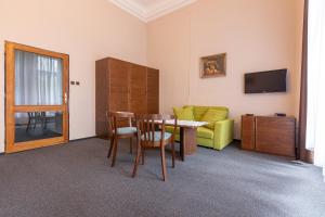een woonkamer met een tafel en een groene bank bij Hotel Slovan Plzeň in Pilsen