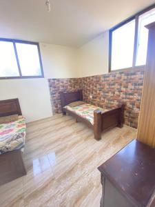 Cette chambre comprend 2 lits et un mur en briques. dans l'établissement Omar home, à Madaba