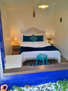 a bedroom with a bed with a blue stool next to it at Casa Lantana in Figueira da Foz