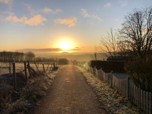 Un camino de tierra con la puesta de sol al fondo en Ferienwohnung Eifelmond, en Nettersheim
