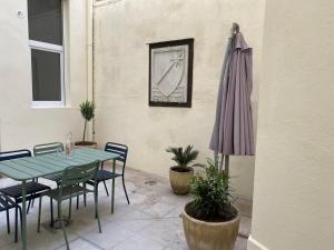 a patio with a table and an umbrella at Appartement cœur de Nimes avec cour in Nîmes