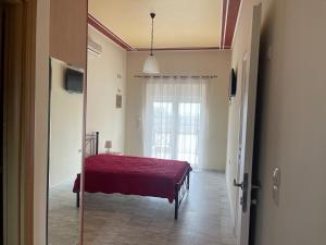 Kouzelis apartments في Kanatádhika: غرفة نوم بسرير ولحاف احمر ونافذة