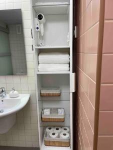 a bathroom with a sink and a shelf with towels at Apartamento Vips Suites in Murcia