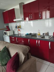 cocina con armarios rojos y sofá en Maison classée 2 étoiles en plein cœur de Margaux en Margaux