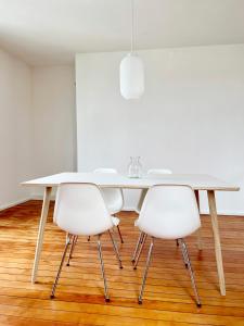 a white dining room table with three white chairs at Haus Münsterblick in Reichenau