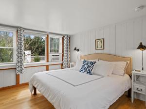 a bedroom with a white bed and two windows at The Seagrove Suites & Guest Rooms in Eastham
