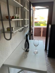eine Theke mit zwei Weingläsern und einer Flasche darauf in der Unterkunft Monolocale Cala Reale in Marinella