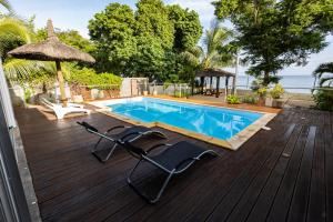 a deck with a swimming pool and two lounge chairs and an umbrella at Les Villas 33 Bis in Baie du Tombeau