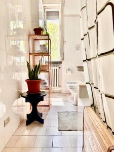 La salle de bains est pourvue de toilettes et d'une plante sur une table. dans l'établissement SM Hospitality LAGHI, à Reggio d'Émilie