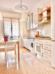 a kitchen with white cabinets and a table with a washing machine at SM Hospitality LAGHI in Reggio Emilia