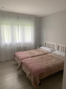 2 camas en un dormitorio con ventana en Apartamentos Cañamal, en Llanes