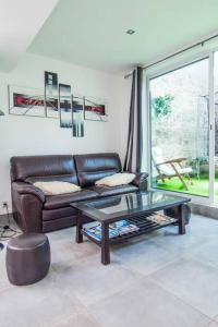 a living room with a leather couch and a table at Appartement avec jardin intérieur 4 pers centre ville in Nemours